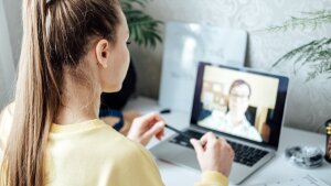 Young woman in front of laptop in online conversation with a second person who can be seen on the laptop