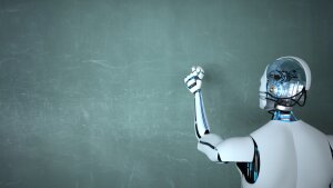 Roboter vor einer Tafel stehend, ein Stück Kreide in der Hand zum Schreiben angesetzt