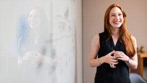 Eine lächelnde Frau hält eine Präsentation vor einem Whiteboard